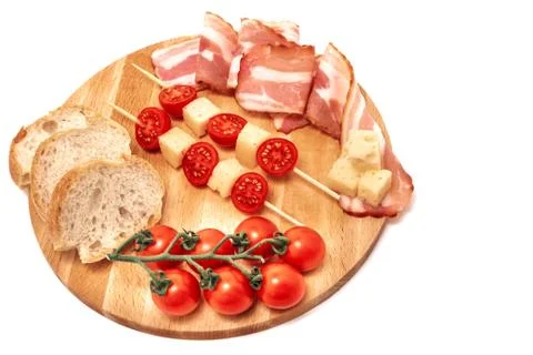 Composition of cheese tomatoes prosciutto and bread on wooden board, isolated Stock Photos