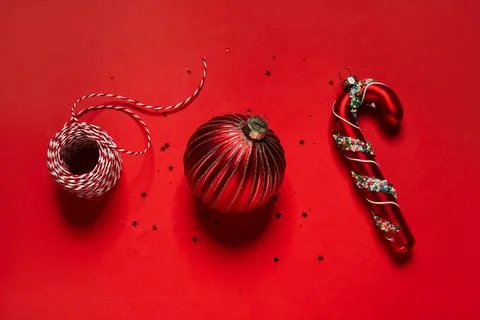 Composition with Christmas balls, threads and confetti on red background, clo Stock Photos