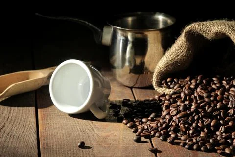 Composition with coffee beans and a cup and cezve on a brown wooden table Stock Photos