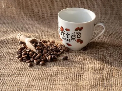 Composition of coffee beans with a mug on a brown material Stock Photos