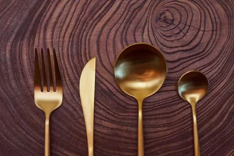 Composition concept.The golden fork, knife, and spoons lies on a slice of a t Stock Photos