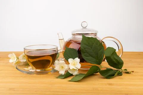 Composition with cup of jasmine tea and flowers on light background Stock Photos