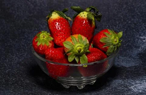Composition of a cup with red strawberries on a dark background with minera.. Stock Photos
