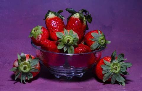 Composition of a cup with ripe strawberries on a delicate pink-violet backg.. Stock Photos