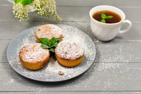 Composition with a cup of tea, cupcakes and white cherry flowers on a wooden Stock Photos