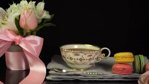 Composition of cup of tea, macaroons, bouquet of flowers, celebration background Stock Footage 156858596