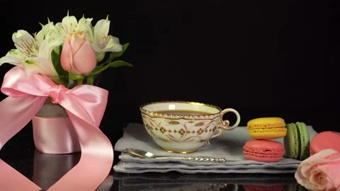 Composition of cup of tea, macaroons, bouquet of flowers, celebration background Stock Footage 157115171