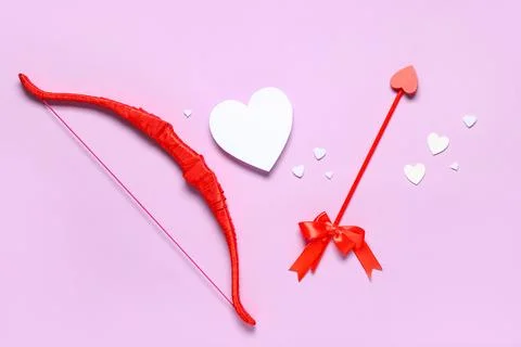 Composition with cupid's bow, arrow and paper hearts on lilac background. Val Stock Photos