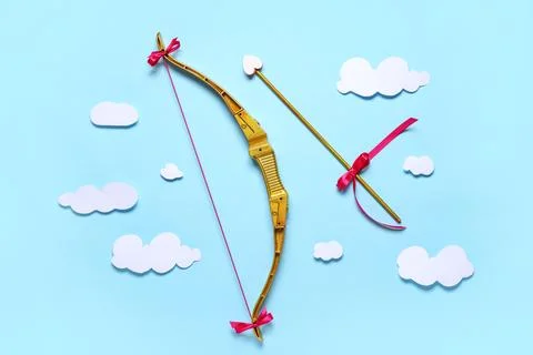 Composition with cupid's bow, arrow and paper clouds on blue background. Vale Stock Photos