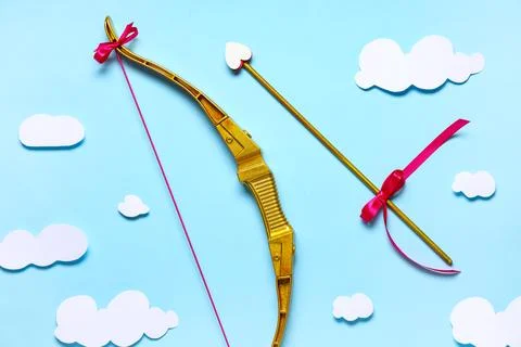 Composition with cupid's bow, arrow and paper clouds on blue background. Vale Stock Photos
