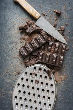 Composition of a dark broken dark chocolate bar, an old knife with a wooden h Foto stock