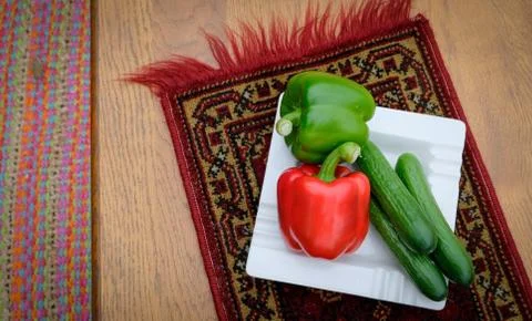 Composition with Different raw Vegetables on white plate on tapestry. paprika Stock Photos