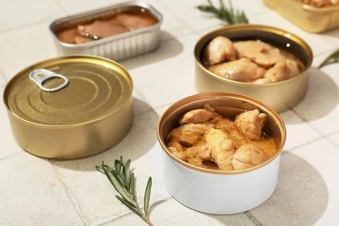 Composition with different tin cans with tasty cod liver on white tile backgr Stock Photos
