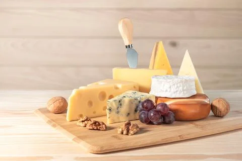 Composition of different types of cheese with walnuts and grapes on wooden ba Stock Photos