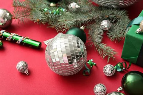 Composition with disco balls, fir tree branches and Christmas decor on red ba Stock Photos