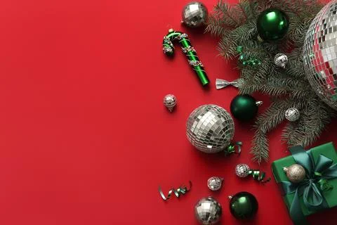 Composition with disco balls, gift box and Christmas decor on red background Stock Photos