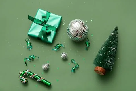 Composition with disco balls, gift box and Christmas decor on green backgroun Stock Photos