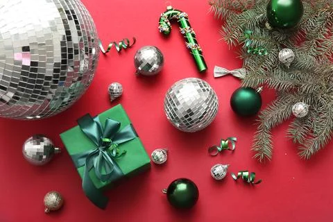 Composition with disco balls, gift box and Christmas decor on red background Stock Photos