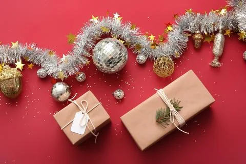 Composition with disco balls, gift boxes and Christmas decor on red backgroun Stock Photos