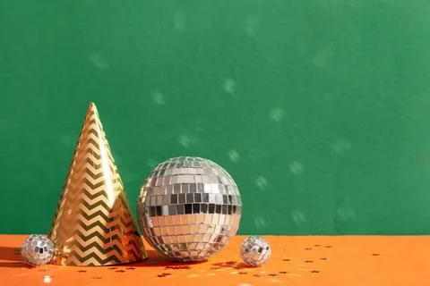 Composition with disco balls, party cone and confetti on color background Stock Photos