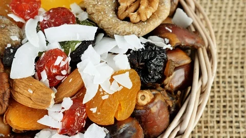 Composition of dried fruits and nuts in small wicker bowl placed on  table. 動画素材 103986713
