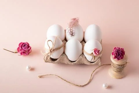 Composition with Easter eggs and eco-decor of dried roses on a beige background. Stock Photos