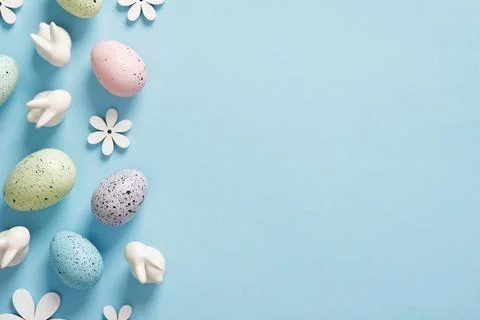 Composition with Easter eggs, bunnies and wooden flowers on blue background.. Stock Photos