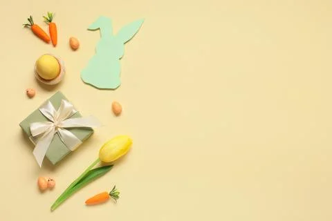 Composition with Easter eggs, gift box and tulip flower on beige background Stock Photos
