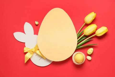 Composition with egg-shaped blank card, Easter eggs and tulip flowers on red  Stock Photos