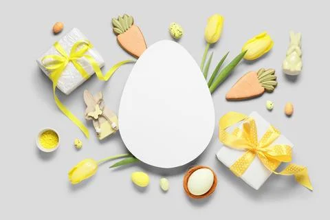 Composition with egg-shaped blank card, gift boxes, Easter eggs and tulip flo Stock Photos