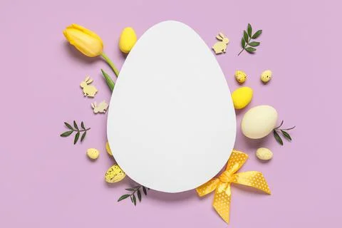 Composition with egg-shaped blank card, Easter eggs and tulip flower on lilac Stock Photos