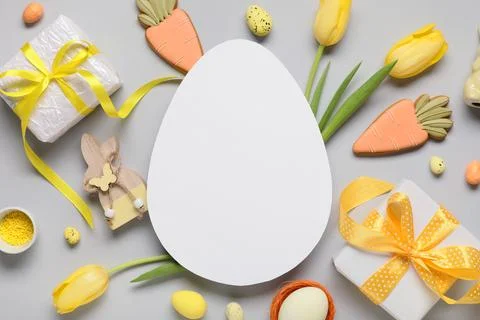 Composition with egg-shaped blank card, gift boxes, Easter eggs and tulip flo Stock Photos