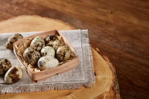 Composition of eggs quail box, eggs on a homespun napkin on a log over wooden Stock Photos