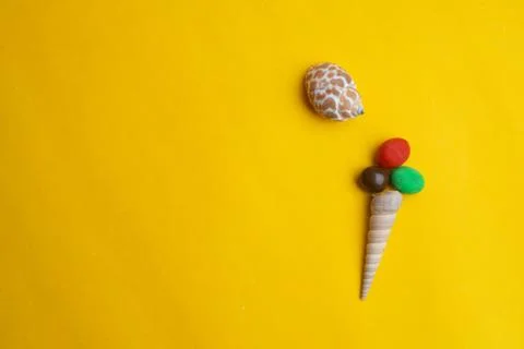 Composition of exotic sea shells on a yellow background. Ice cream concept. Stock Photos