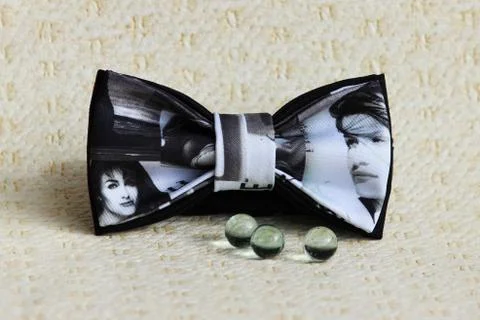 Composition: Extravagant black and white bow tie and glass balls on a beige Stock Photos
