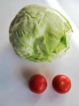 Composition featuring crisp green head lettuce and two bright red tomatoes Stock Photos