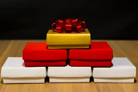 Composition of festive boxes of white, red and gold color on a wooden table. Stock Photos