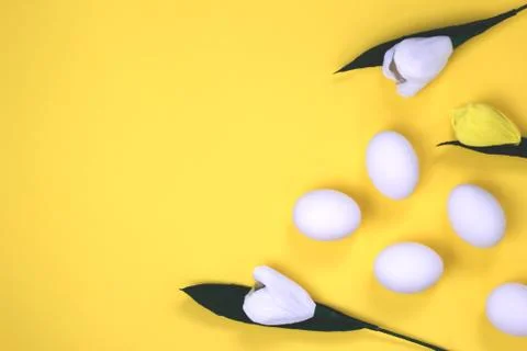Composition of flowers and Easter eggs on yellow background, from above Stock Photos