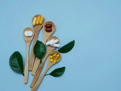 Composition in the form of a bouquet of capsules and tablets in wooden spoons Stock Photos