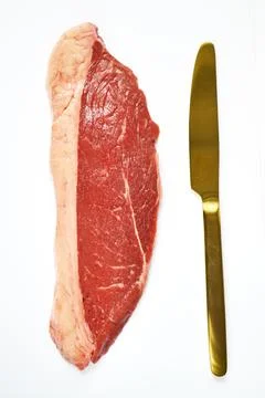 Composition of fresh and raw beef steak and knife on a white background Stock Photos
