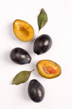 Composition of fresh plums with leaves on light background. View from above. Stock Photos