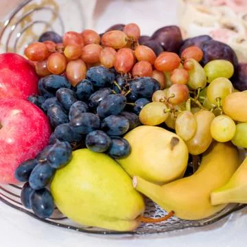 A composition of fruits on a table on a transparent dish. Apples, pears, plum Foto stock