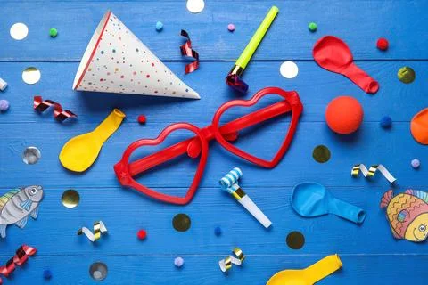 Composition with funny glasses, party hat, balloons and confetti on blue wood Stock Photos