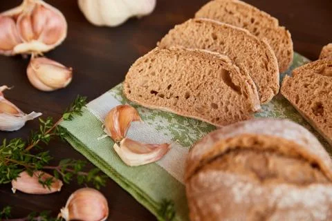 Composition of garlic and bread on a dark wooden table. Freshly baked hand-ma Stock Photos