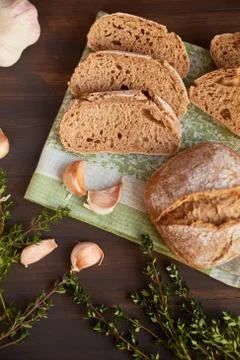 Composition of garlic and bread on a dark wooden table. Freshly baked hand-ma Stock Photos