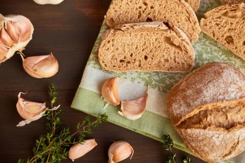 Composition of garlic and bread on a dark wooden table. Freshly baked hand-ma Stock Photos