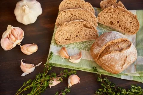 Composition of garlic and bread on a dark wooden table. Freshly baked hand-ma Stock Photos