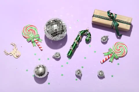 Composition with gift box, disco balls, lollipops and Christmas decor on lila Stock Photos