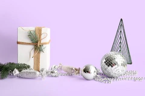 Composition with gift box, disco balls and Christmas decor on lilac backgroun Stock Photos