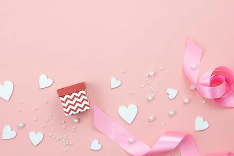 Composition with gift box, pink ribbons, white hearts and pearls on a pink Stock Photos